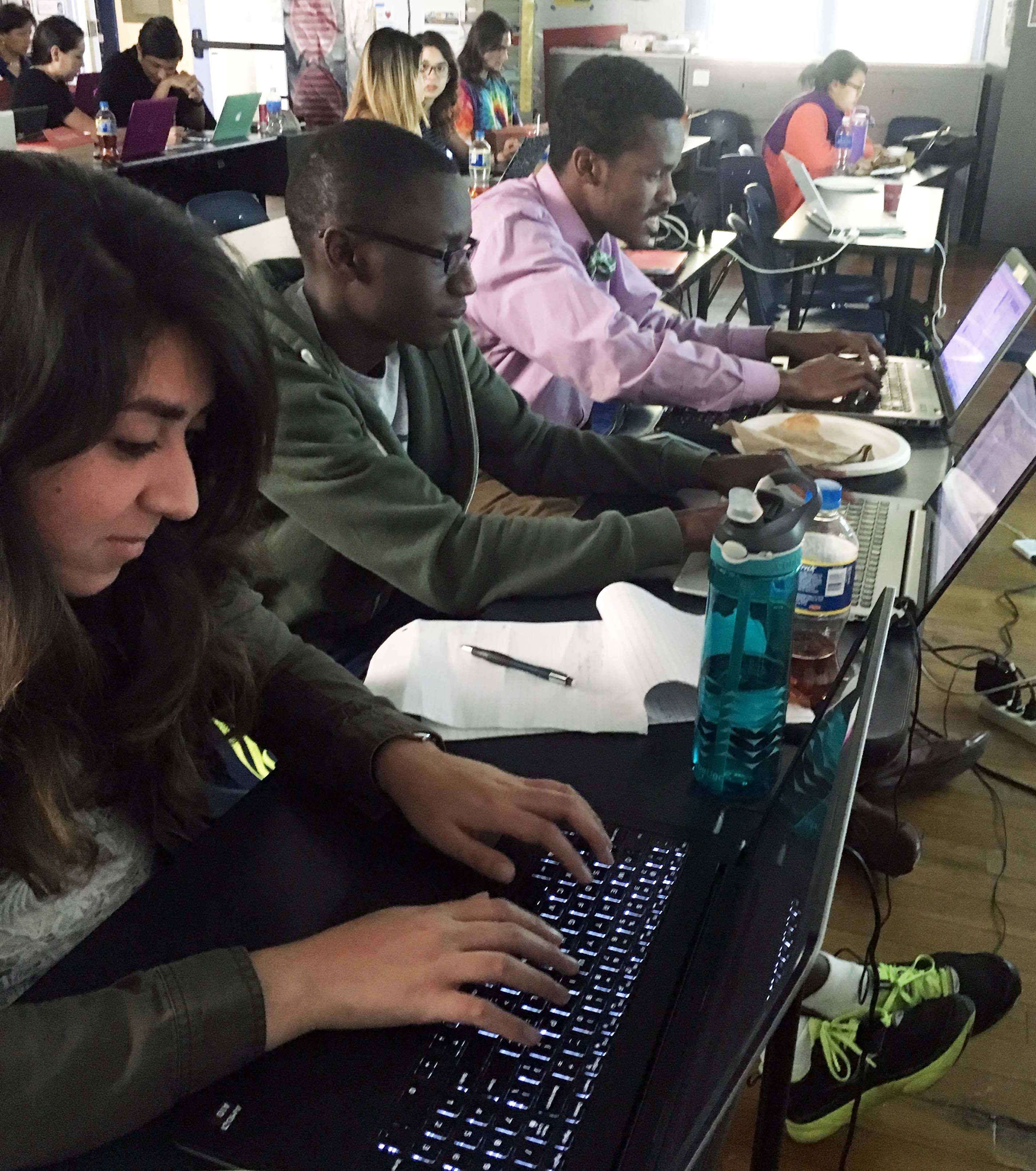 Photo of students using their computers to code in python